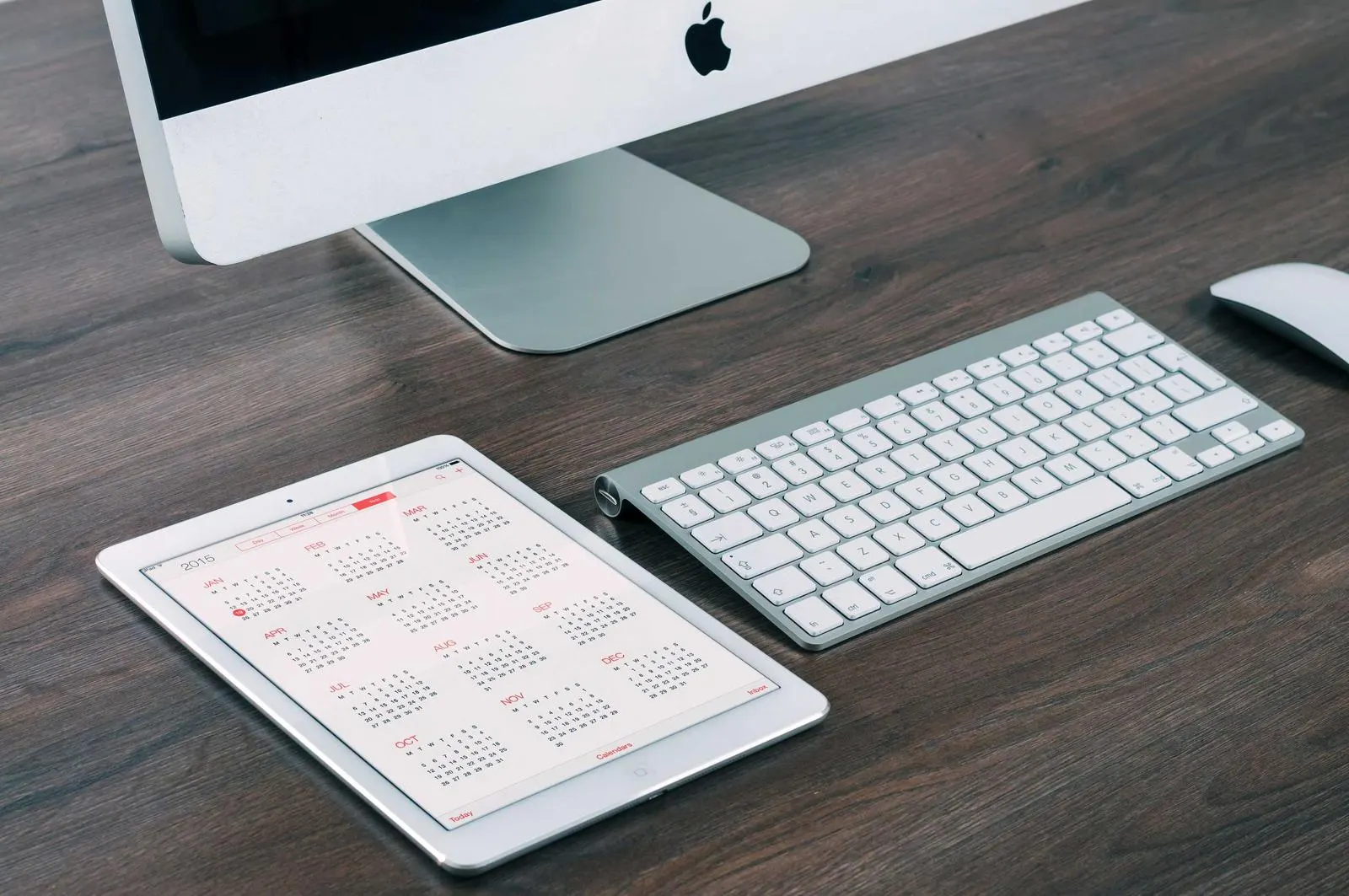مانیتور iMac، کیبورد بی‌سیم و تبلت روی میز چوبی؛ یک اپلیکیشن برای همه‌ی سیستم‌عامل‌های دسکتاپ